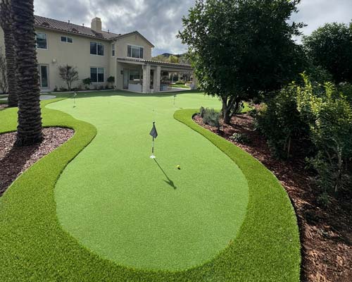 Residential artificial putting green with curved design in backyard setting