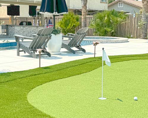 Poolside artificial putting green in residential backyard with practice hole