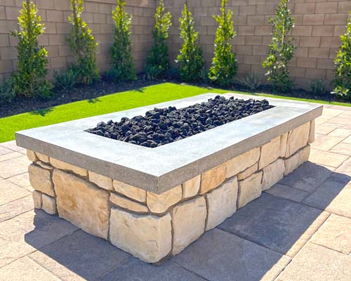 Custom-Fire-Pit-500x400 A stone fire pit sitting on a patio.