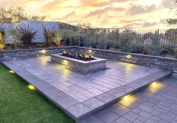 WEBSITE-HOME-PAGE-THUMBNAILS-Hardscape-No-Text Custom paver patio with built-in fire pit, retaining wall seating, and integrated landscape lighting
