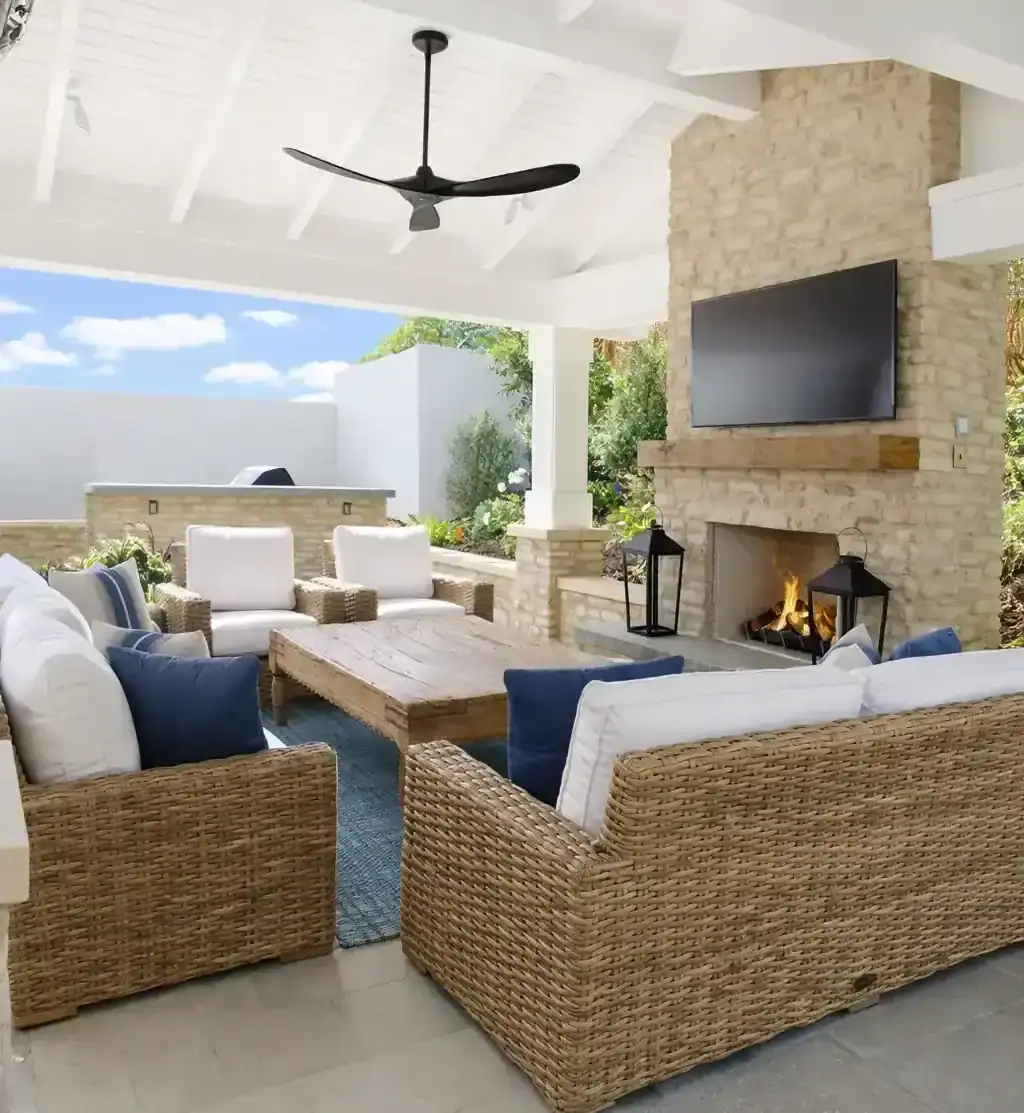 outdoor-living-patio-fireplace-seating covered outdoor living patio with wicker seating, fireplace, and mounted TV for backyard entertainment