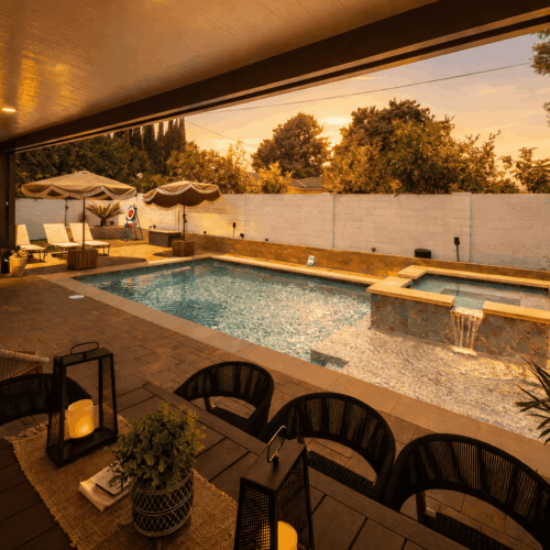 Backyard pool and spa with waterfall feature, poolside seating, and sunset outdoor entertaining space.